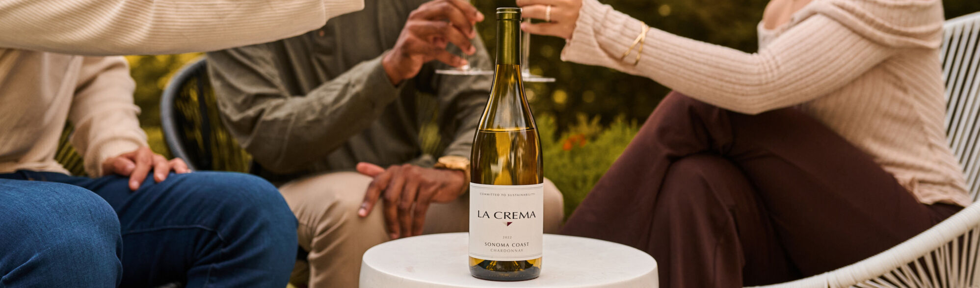 A group of friends drinking a bottle of La Crema Chardonnay wine